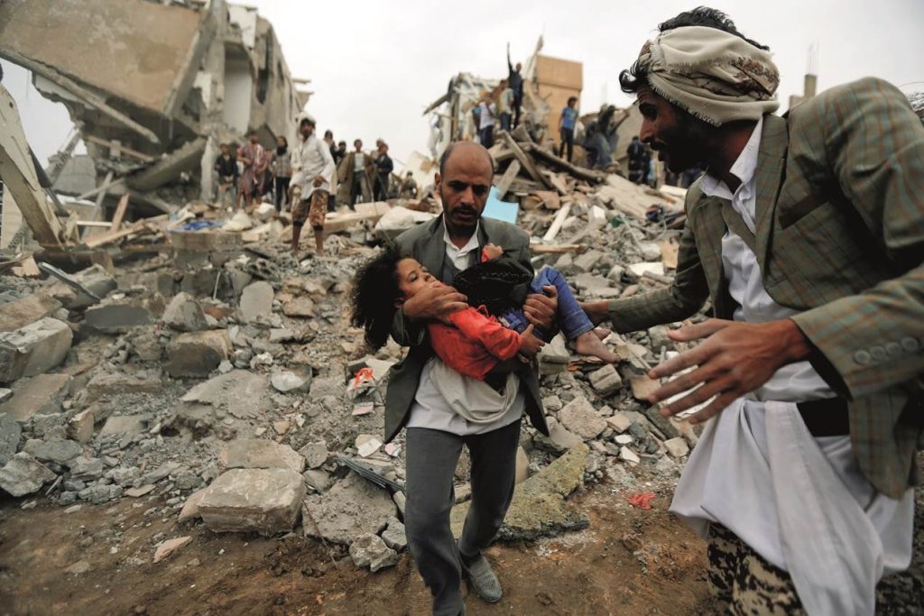 Guerre au Yémen, homme transportant petite fille blessée par des bombardements