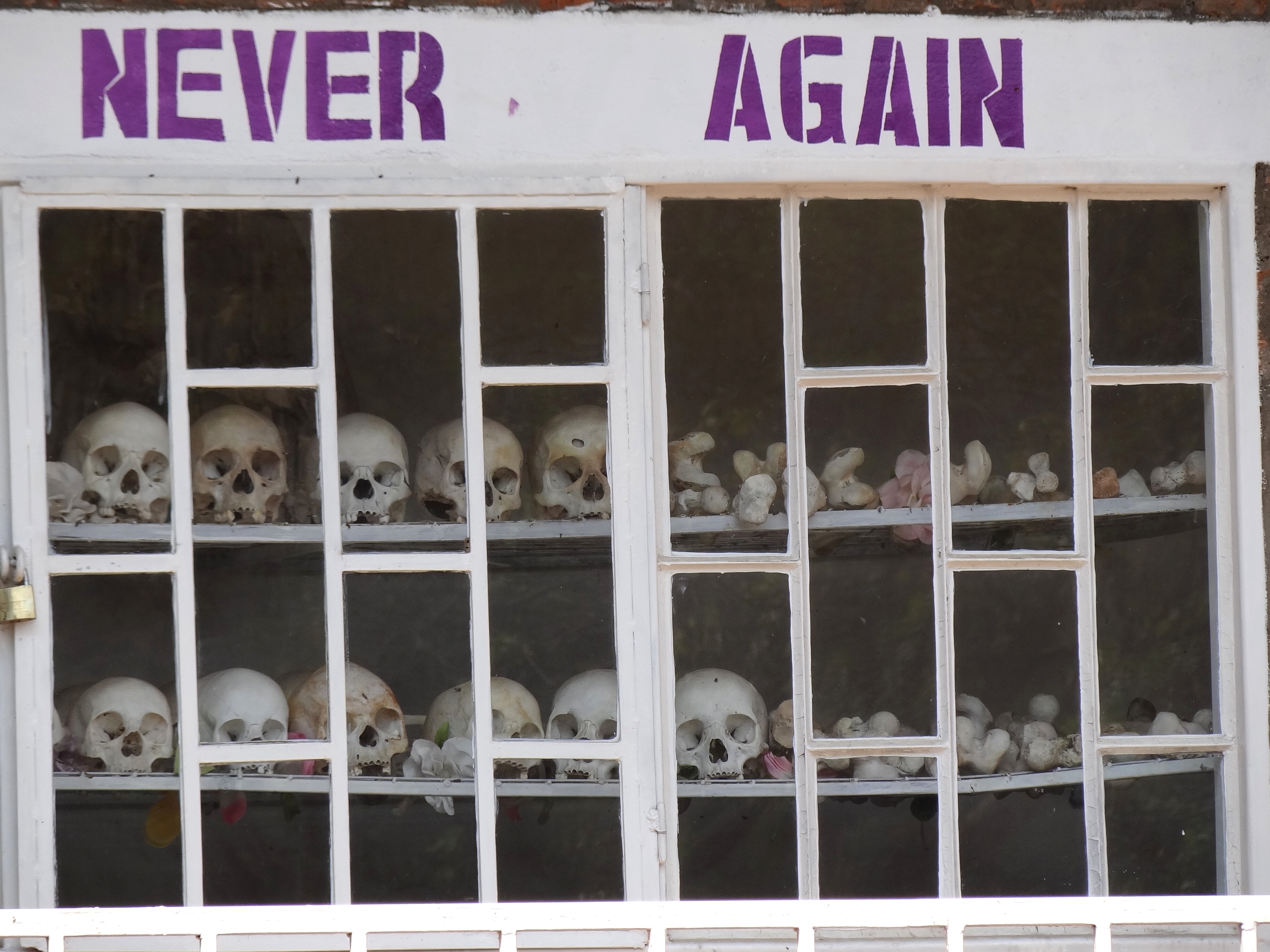 Never_Again_-_With_Display_of_Skulls_of_Victims_-_Courtyard_of_Genocide_Memorial_Church_-_Karongi-Kibuye_-_Western_Rwanda_-_02